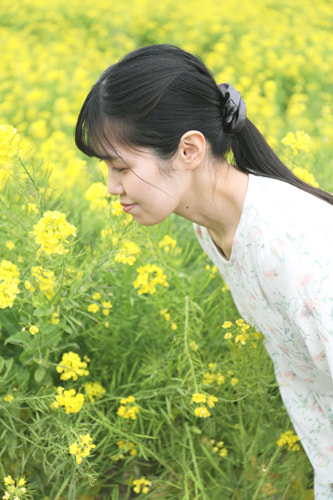 菜の花を見つめる女性